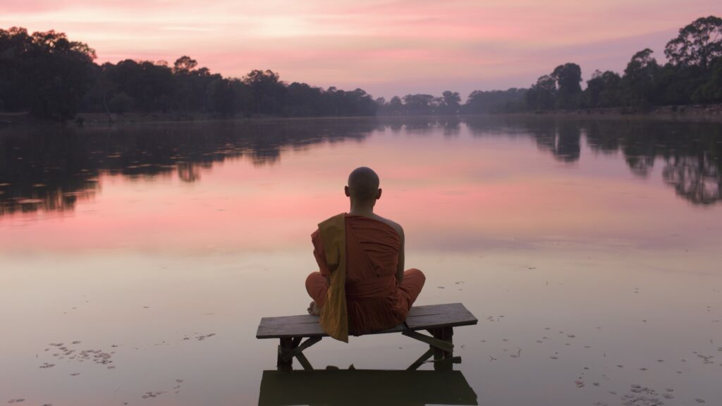 Buddhistischer Mönch meditiert am Wasser